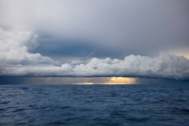 Kuzey Bali, Endonezya açıklarında fırtına bulutları. Bulutlardan okyanusa dökülen yağmur. Öndeki mavi deniz. 