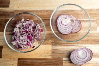 Tahta bir yüzeyde cam kaselerde dilimlenmiş ve doğranmış kırmızı soğanlar.