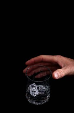 Siyah arka planda buzlu bir bardağa uzanan bir el. Ürün tasarımı, reklam planları ya da menü görselleri için temiz negatif alanı olan siyah bir stüdyonun arka planında fotoğraflanmış..