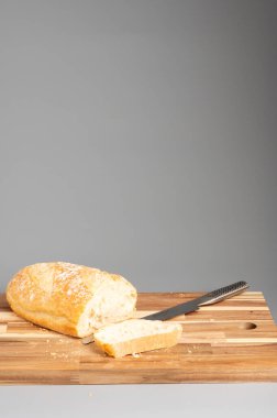 Dilimlenmiş bir somun ekmek, bir bıçakla tahta bir kesme tahtasının üzerine yerleştirilmiş. Tarifler, bloglar ve mutfak tasarımı için uygun Rustik ahşap kesim tahtası arka planı.