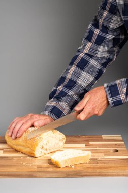 Tahta kesme tahtasıyla taze ekmek dilimleyen biri. Tarifler, bloglar ve mutfak tasarımı için uygun Rustik ahşap kesim tahtası arka planı.