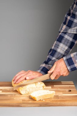 Tahta kesme tahtasında ekmek dilimleyen biri. Tarifler, bloglar ve mutfak tasarımı için uygun Rustik ahşap kesim tahtası arka planı.