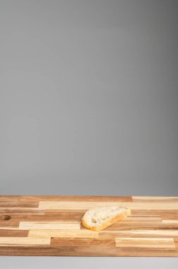 Gri arkaplanı olan ahşap bir yüzeyde tek bir dilim ekmek. Tarifler, bloglar ve mutfak tasarımı için uygun Rustik ahşap kesim tahtası arka planı.