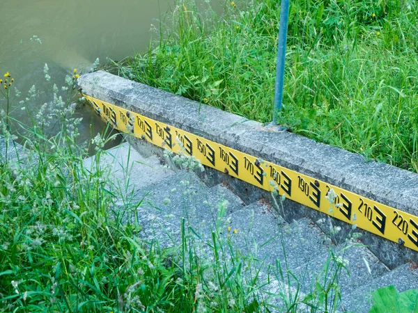 堤防上の黄色の背景に石段と黒の文字と水位インジケータ — ストック写真
