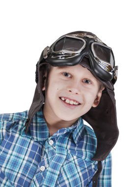 Kafası ve omuzları beyaz arka planda kameraya mutlu bir şekilde bakan, deri şapkalı ve geleneksel motosiklet gözlüklü bir beyaz çocuk..