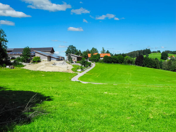 Bavarian hilly landscape with a farm near the Schwaltenweiher in summer 2022.