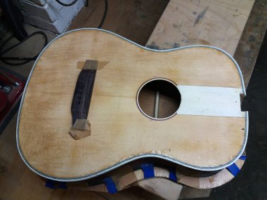 Tamamlanmamış eski bir akustik gitarın üst görüntüsü köprüyü ayarlarken.