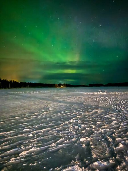 The green aurora borealis glows above a wide frozen landscape, illuminating the snow under the Arctic night sky. This peaceful winter scene captures the magic and stillness of the far north. Perfect for illustrating nature, astronomy, and winter