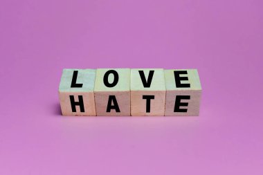 Tahta blokları aşk ve nefret dolu sözlerle çevir. Pembe arka planda izole edilmiş.