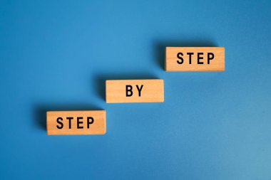 Adım adım ahşap bloklardaki merdivenlerde mavi arka planda izole edilmiş. Başarı ya da kariyer kavramı