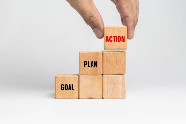 Erkek eli hedefi, planı, eylem sözcüklerini beyaz arkaplanda izole edilmiş tahta blokların üzerine koyar