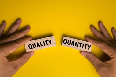 Erkek el ele tutuşma kalitesi ve ahşap bloklardaki nicelik kelimeleri sarı arka planda izole edilmiş.