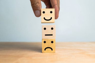 Erkek el yığınları üzgün, düz ve mutlu yüz ifadeleri ahşap masanın üzerindeki tahta küplerin üzerinde.