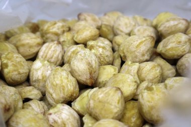 A macro close-up of a pile of shelled candlenut seeds (kemiri), showing their texture and color, a raw cooking ingredient for Southeast Asian spice pastes.