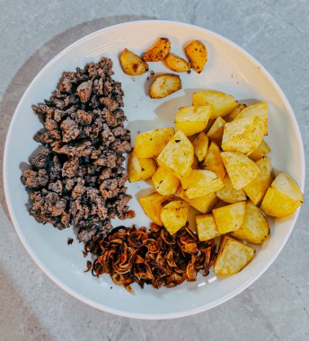 Üst manzara: Baharatlı sığır eti, patates kızartması ve kızarmış soğan. Besleyici bir yemek reklamı için mükemmel..