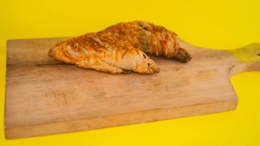 Lezzetli ve lezzetli bir Endonezya yemeği, muz boleni, rendelenmiş peynirle kaplanmış, ahşap bir tahtanın üzerinde..