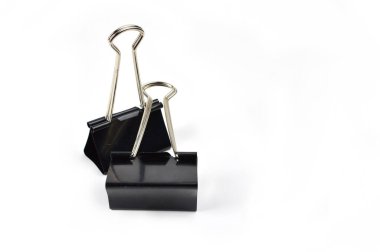 Close-up photo of two black binder clips with metal handles placed on a clean white surface, used for holding and organizing documents.
