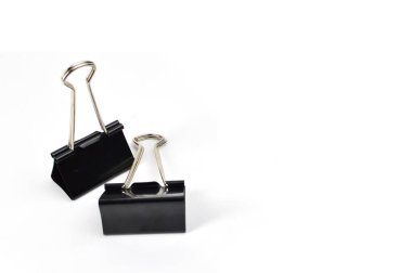 Close-up photo of two black binder clips with metal handles placed on a clean white surface, used for holding and organizing documents.