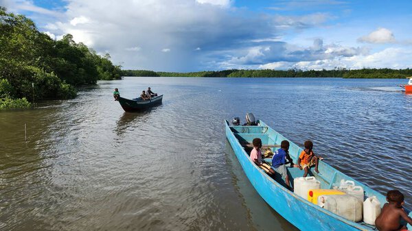 Papuan locals cross the sea in a wooden boat near coastal Papua, Indonesia. Daily transportation between islands. Captured on June 28, 2025. Papua, Indonesia.