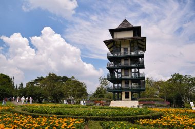 Taman Bunga Nusantara, Cianjur 'da bulutların ve mavi gökyüzünün arka planında yer alan yüksek kule ve çiçek bahçesinin güzelliği..