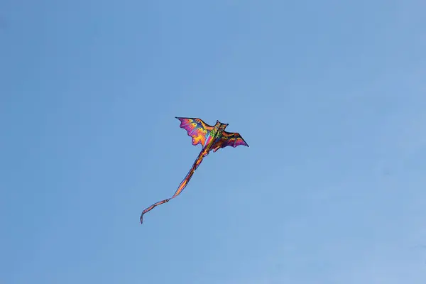 Renkli ejderha şekilli uçurtma açık mavi gökyüzünde uçuyor güneşli bir günde