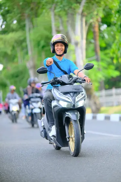 Kaskla gezerken modern bir scooter süren mutlu genç adam.