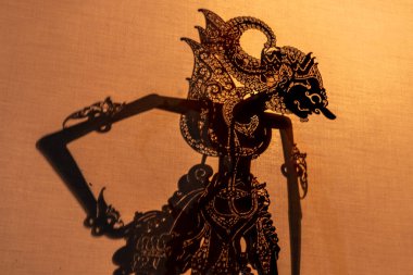 Silhouette of traditional Javanese wayang kulit puppet projected on screen. Unique cultural heritage, handmade leather art, folklore performance, and Indonesian shadow theater