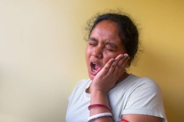 Genç Hintli kadın diş ağrısı ya da diş hastalığından dolayı elleri ve elleri birbirine değen sıradan kıyafetler giyiyor. dişçi ve diş sorunları kavramı.