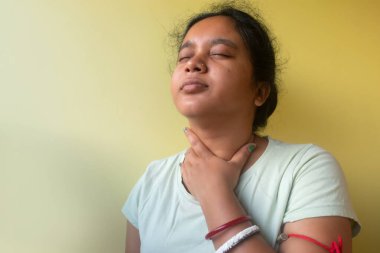 Güzel genç Hintli kadının eli ile hasta boynuna dokunduğu yakın plan. Boğazı ağrıyor, yutkunuyor. Boğaz ağrısı kavramı.