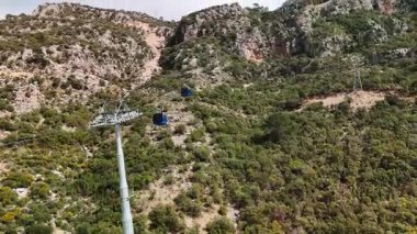 Cable Car in Oludeniz, Turkey Cable car ascending the pine-covered mountains of Oludeniz, Turkey. The Mediterranean Sea and scenic hills in the background. Drone footage shot at 60fps, perfect for travel, tourism, transportation, and nature themes.