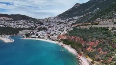 Stunning aerial view of Kalkan, Turkeys picturesque bay. White Mediterranean houses and luxury villas descend to the sunny marina with yachts. Crystal-turquoise waters and islands in the distance. Perfect for travel, resort projects. 4K 60 fps.