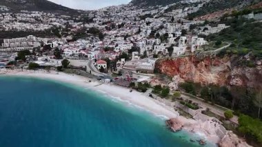 Stunning aerial view of Kalkan, Turkeys picturesque bay. White Mediterranean houses and luxury villas descend to the sunny marina with yachts. Crystal-turquoise waters and islands in the distance. Perfect for travel, resort projects. 4K 60 fps.