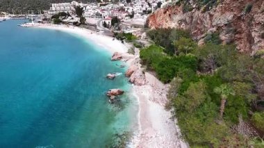 Stunning aerial view of Kalkan, Turkeys picturesque bay. White Mediterranean houses and luxury villas descend to the sunny marina with yachts. Crystal-turquoise waters and islands in the distance. Perfect for travel, resort projects. 4K 60 fps.