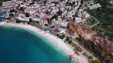 Stunning aerial view of Kalkan, Turkeys picturesque bay. White Mediterranean houses and luxury villas descend to the sunny marina with yachts. Crystal-turquoise waters and islands in the distance. Perfect for travel, resort projects. 4K 60 fps.