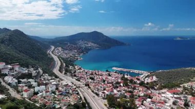 Stunning aerial view of Kalkan, Turkeys picturesque bay. White Mediterranean houses and luxury villas descend to the sunny marina with yachts. Crystal-turquoise waters and islands in the distance. Perfect for travel, resort projects. 4K 60 fps.