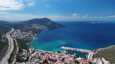 Stunning aerial view of Kalkan, Turkeys picturesque bay. White Mediterranean houses and luxury villas descend to the sunny marina with yachts. Crystal-turquoise waters and islands in the distance. Perfect for travel, resort projects. 4K 60 fps.