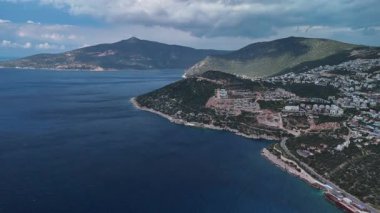 Stunning aerial view of Kalkan, Turkeys picturesque bay. White Mediterranean houses and luxury villas descend to the sunny marina with yachts. Crystal-turquoise waters and islands in the distance. Perfect for travel, resort projects. 4K 60 fps.