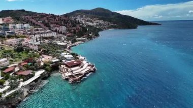 Stunning aerial view of Kalkan, Turkeys picturesque bay. White Mediterranean houses and luxury villas descend to the sunny marina with yachts. Crystal-turquoise waters and islands in the distance. Perfect for travel, resort projects. 4K 60 fps.