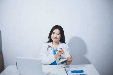 Doktorun odasında dizüstü bilgisayarla çalışan orta yaşlı bir kadın doktor.