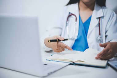 Doktorun odasında dizüstü bilgisayarla çalışan orta yaşlı bir kadın doktor.