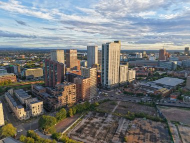 Aerial view of a bustling city showcasing a mix of modern skyscrapers and open land. The scene captures the life and energy of a vibrant urban environment under a bright sky.