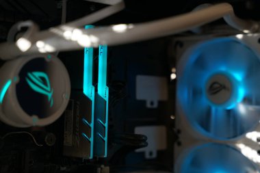 A close-up view of a gaming PC showcasing vibrant blue lights from RAM sticks and cooling fans. The internal structure highlights advanced components designed for high performance.