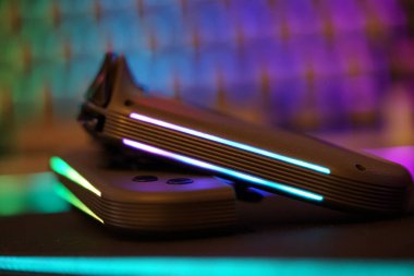 Close-up view of two gaming controllers with glowing lights, showcasing modern design and technology against a colorful background. Ideal for gaming enthusiasts.