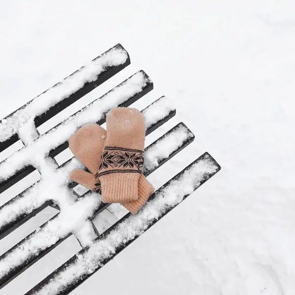 Un par de manoplas beige con un patrón de punto oscuro se encuentra en ...