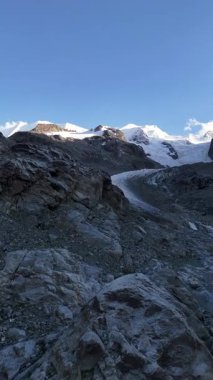 İsviçre 'nin Engadin Vadisi' ndeki Morteratsch Buzulu 'ndan yükselen buzul nehrinin manzarası. Fotoğraf, karla kaplı zirveleri, kayaları ve mavi buzul suyuyla dramatik alp manzarasını gösteriyor. Seyahat, turizm ve çevre için mükemmel.