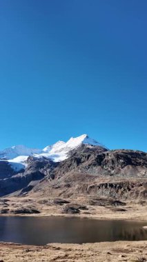 İsviçre 'nin İsviçre Alpleri' ndeki Bernina Geçidi üzerindeki Lago Bianco 'nun (Beyaz Göl) havadan görünüşü. Dağlarla, buzullarla ve ünlü Bernina demiryollarıyla çevrili manzaralı bir dağ deposu. Seyahat, turizm, doğa, manzara ve macera kavramları için mükemmel..