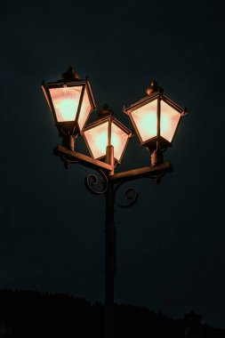 İsviçre Alplerinde dramatik sonbahar günbatımı dağ zirveleri ve mor ve turuncu gökyüzünün altındaki orman silueti. İsviçre 'de sonbaharın güzelliğini yansıtan barışçıl ama atmosferik bir alp manzarası.