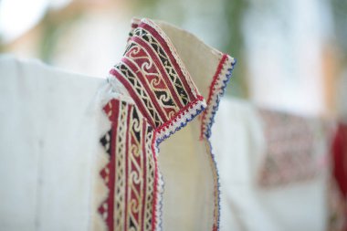 Orijinal geleneksel bir giysinin yakasına yakın çekim, ayrıntılı ve renkli nakış sergileniyor, ustalıklı işçilik vurgulanıyor..
