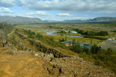 Kuzey Amerika ve Avrasya tektonik plakaları arasındaki yarık vadisinin yer aldığı İzlanda 'daki Thingvellir Milli Parkı manzarası, uçurumlar, yeşillikler, su kaynakları ve geleneksel binalar.