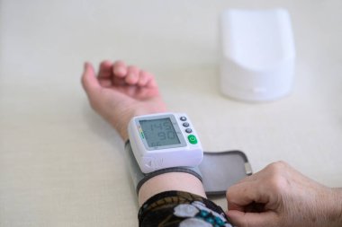 Üst düzey bir kadın kan basıncını 145 / 90 mmmHg 'lik dijital bir monitörle ölçüyor, hipertansiyon farkındalığı, ev testleri ve kıdemli refahını gösteriyor..